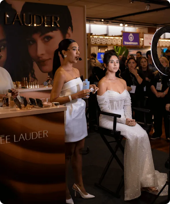 Imagem de uma mulher maquiando uma modelo no evento casar.com no estande da Estee Launder