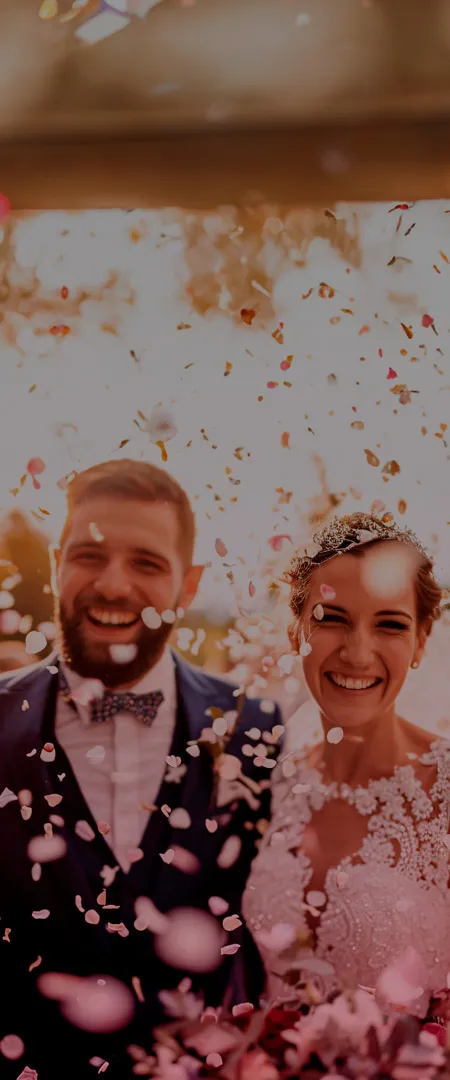 Banner Mobile Casar.com - Planejamento de Casamento na Palma da Mão Casal de noivos, sorrindo e celebrando, caminhando enquanto são cobertos por rosas