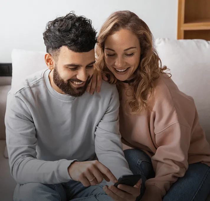 Casal Feliz com a Lista de Casamento em Dinheiro Casal sorrindo olhando celular
